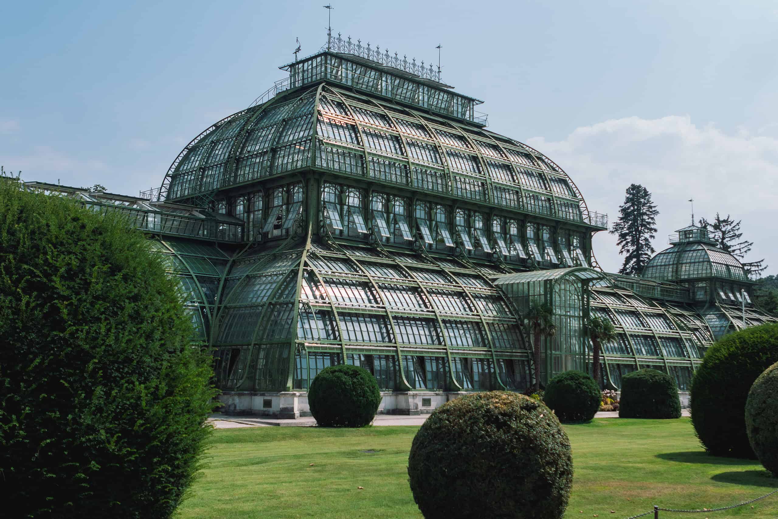 Vintage glass greenhouse with lush green surroundings.